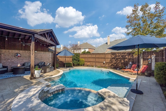 view of swimming pool featuring a patio, a fenced backyard, a pool with connected hot tub, and an outdoor fire pit