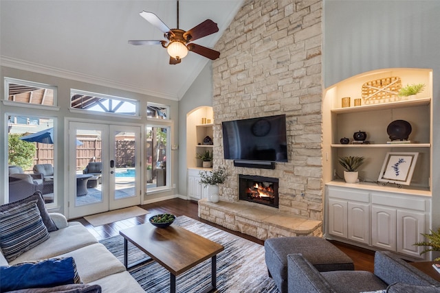 living area with a stone fireplace, built in features, french doors, and wood finished floors