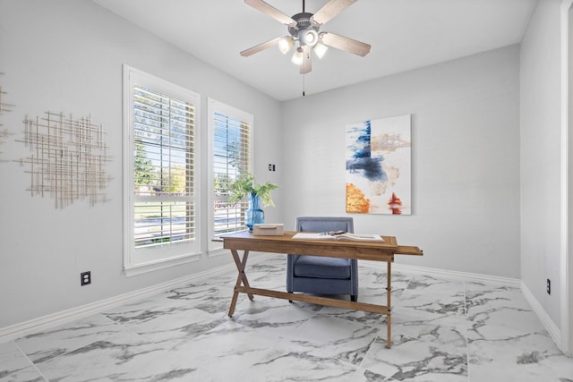 office area with a healthy amount of sunlight, a ceiling fan, marble finish floor, and baseboards