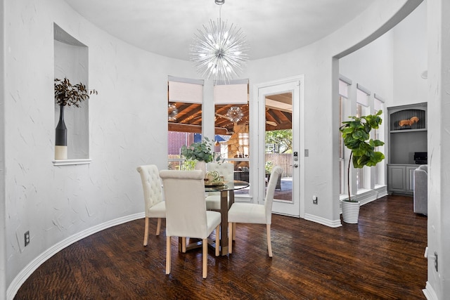 dining area featuring wood finished floors, baseboards, a textured wall, and a chandelier