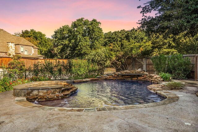 pool at dusk with a fenced backyard and a fire pit