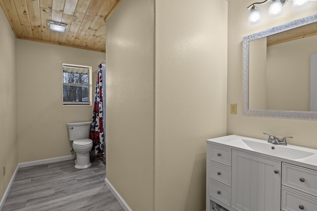 bathroom featuring vanity, wood finished floors, baseboards, wooden ceiling, and toilet