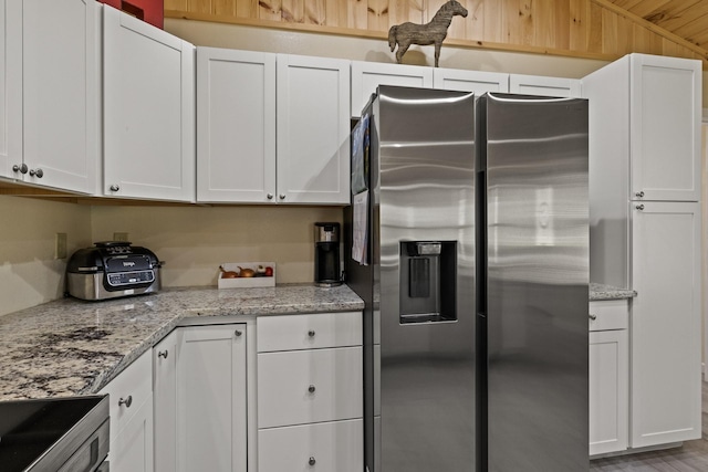 kitchen with light stone counters, appliances with stainless steel finishes, and white cabinetry