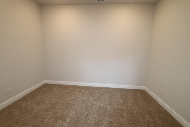 carpeted spare room featuring baseboards