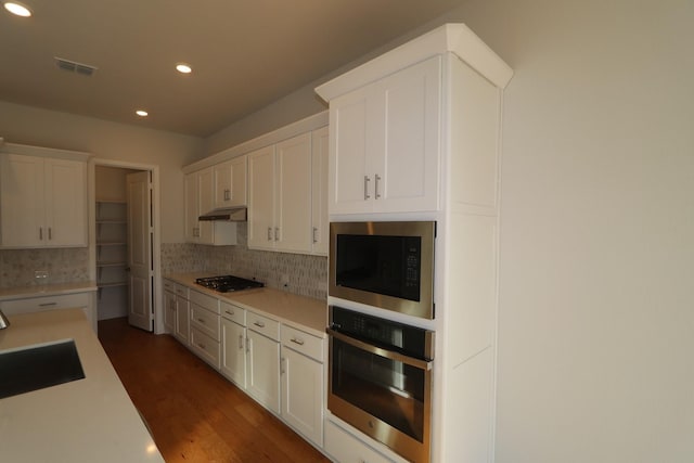 kitchen with visible vents, gas stovetop, built in microwave, a sink, and stainless steel oven