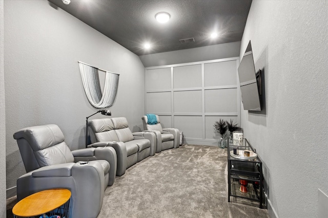 carpeted home theater with a textured wall, visible vents, and a textured ceiling