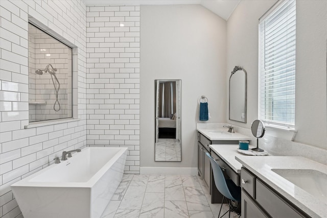 ensuite bathroom with a freestanding bath, lofted ceiling, two vanities, marble finish floor, and a sink