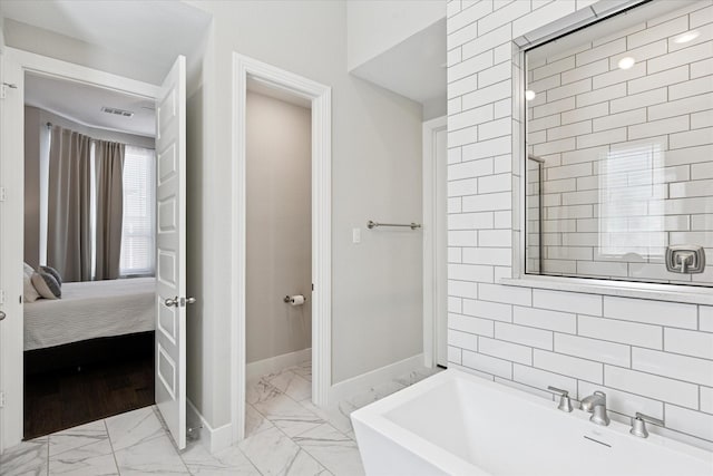 full bath featuring baseboards, marble finish floor, a bathtub, and connected bathroom