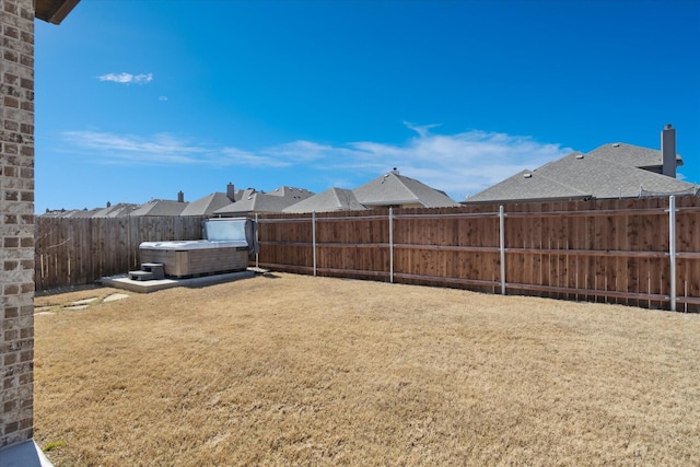 view of yard with a hot tub and a fenced backyard