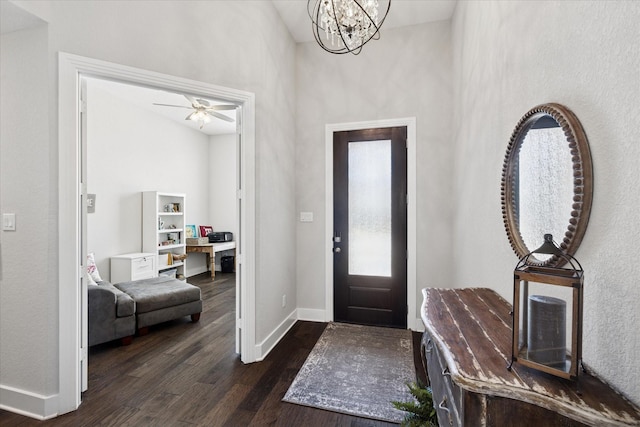 entryway with dark wood finished floors, a notable chandelier, and baseboards