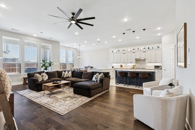 living room featuring a ceiling fan, dark wood-style floors, visible vents, baseboards, and recessed lighting