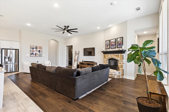 living area featuring recessed lighting, a fireplace, arched walkways, ceiling fan, and dark wood-type flooring