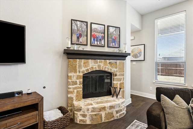 living area featuring a stone fireplace, wood finished floors, and baseboards