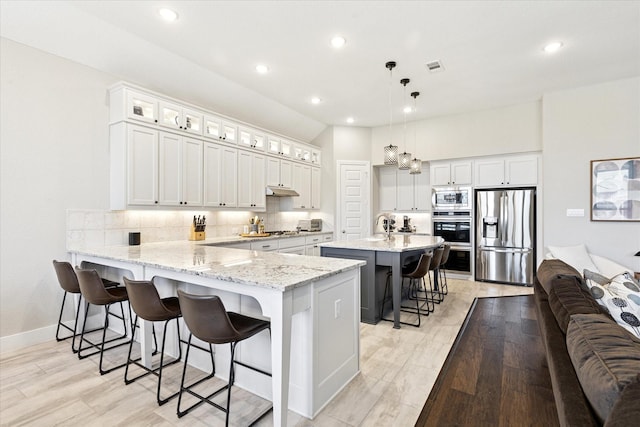 kitchen featuring a peninsula, stainless steel appliances, decorative backsplash, glass insert cabinets, and a kitchen bar