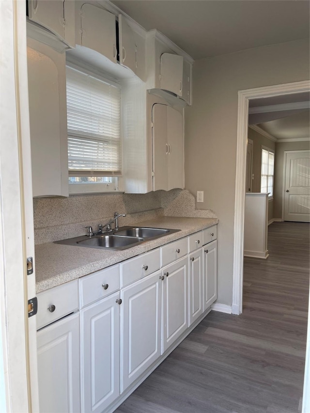 kitchen with a sink, dark wood finished floors, white cabinets, light countertops, and baseboards