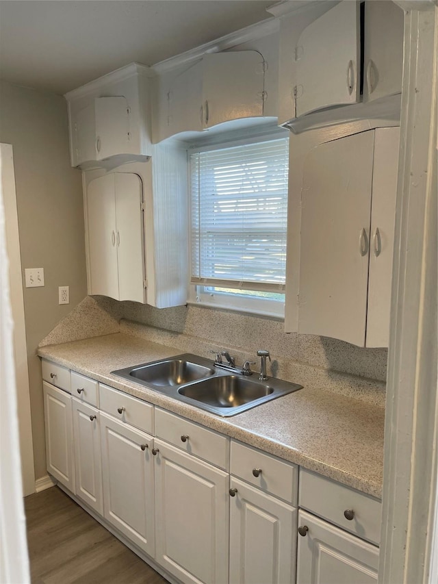 kitchen featuring light wood-style flooring, white cabinetry, light countertops, and a sink