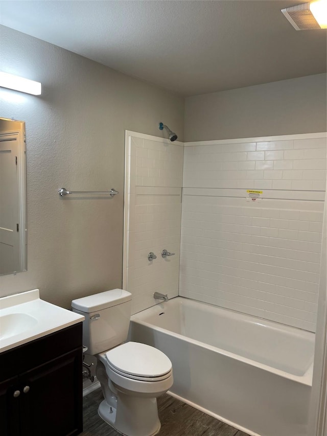 full bathroom with vanity, washtub / shower combination, wood finished floors, visible vents, and toilet