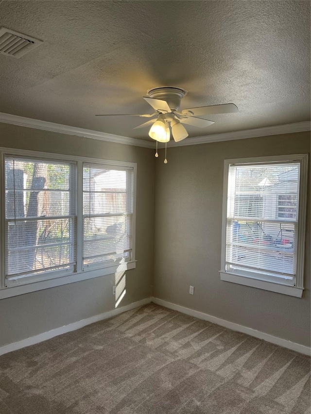 empty room featuring visible vents, plenty of natural light, carpet, and ornamental molding