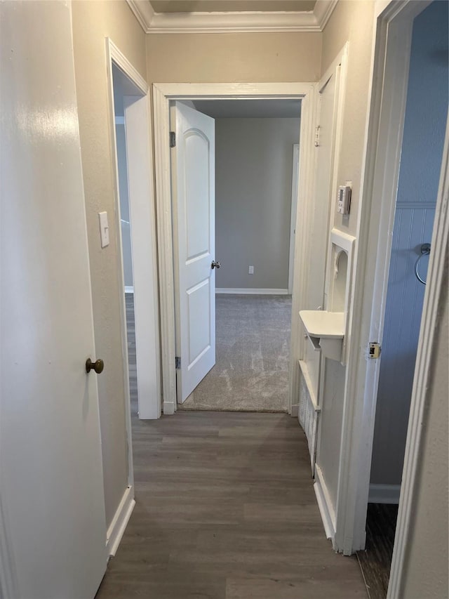 corridor with dark wood finished floors, baseboards, and ornamental molding