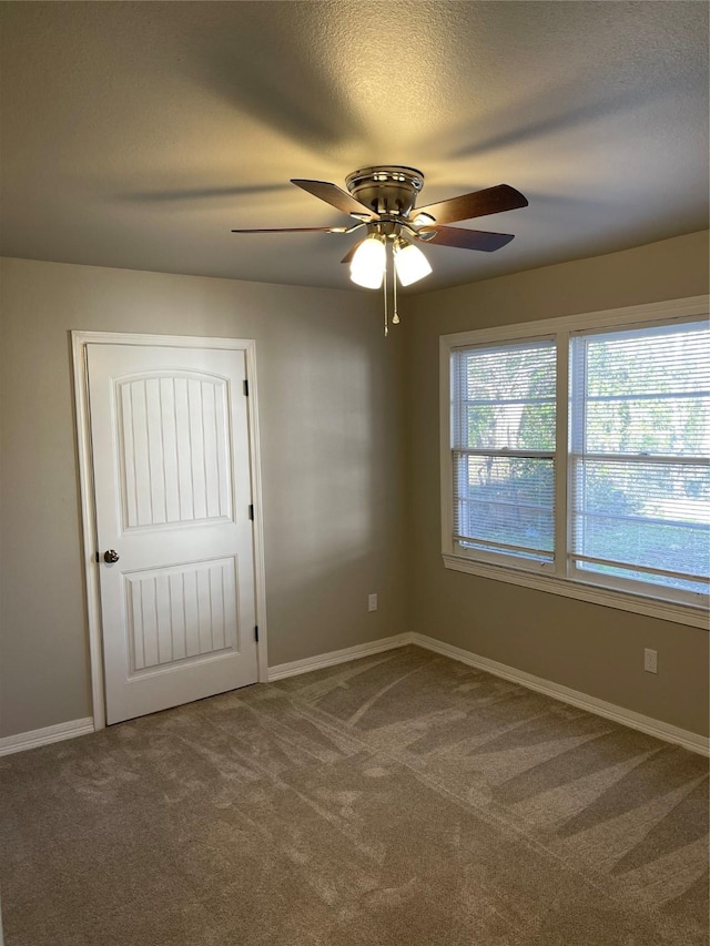 carpeted empty room with baseboards, a textured ceiling, and ceiling fan