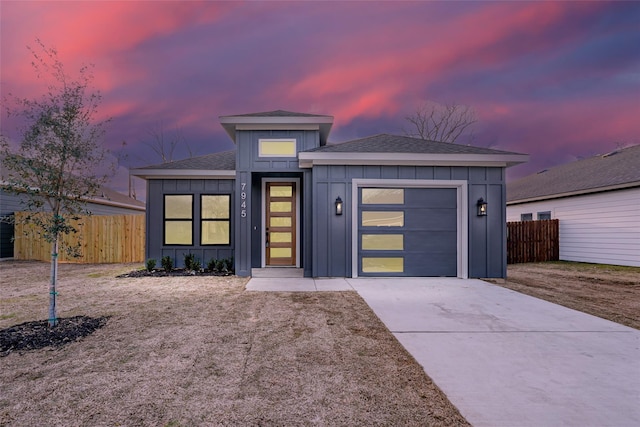 view of front of property featuring a garage, board and batten siding, concrete driveway, and fence