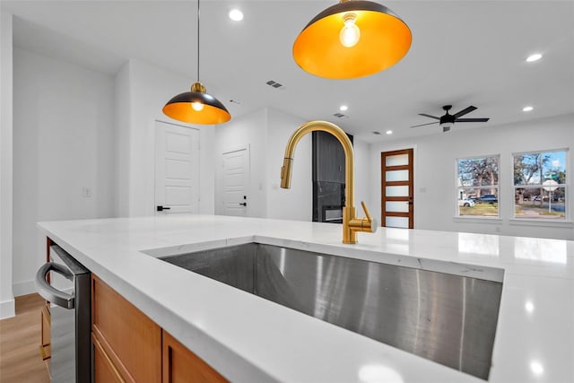 kitchen featuring visible vents, a sink, stainless steel dishwasher, recessed lighting, and brown cabinetry