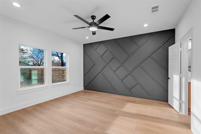 spare room featuring visible vents, light wood-style floors, a decorative wall, baseboards, and an accent wall