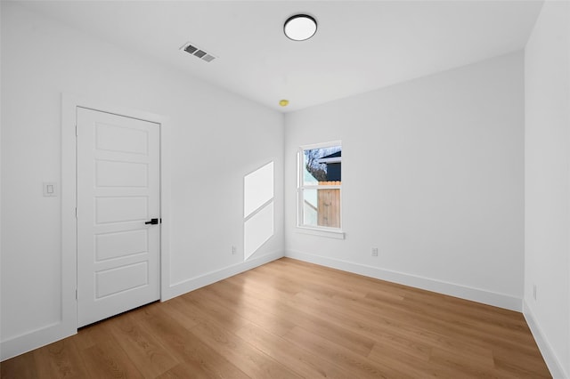 unfurnished room featuring light wood finished floors, visible vents, and baseboards