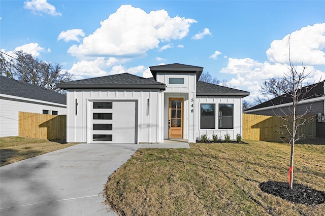 view of front facade with board and batten siding, fence, a front yard, a garage, and driveway