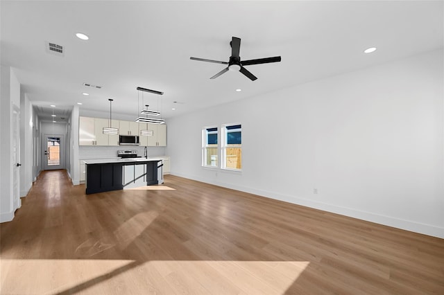 unfurnished living room with light wood-type flooring, visible vents, attic access, and recessed lighting