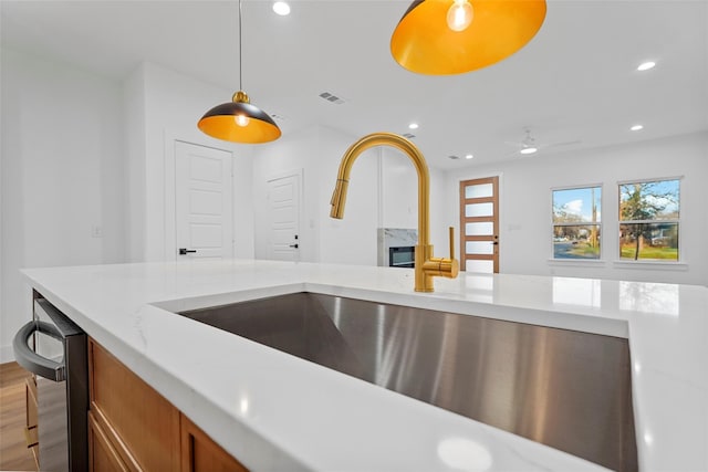 kitchen with visible vents, brown cabinets, pendant lighting, a sink, and recessed lighting