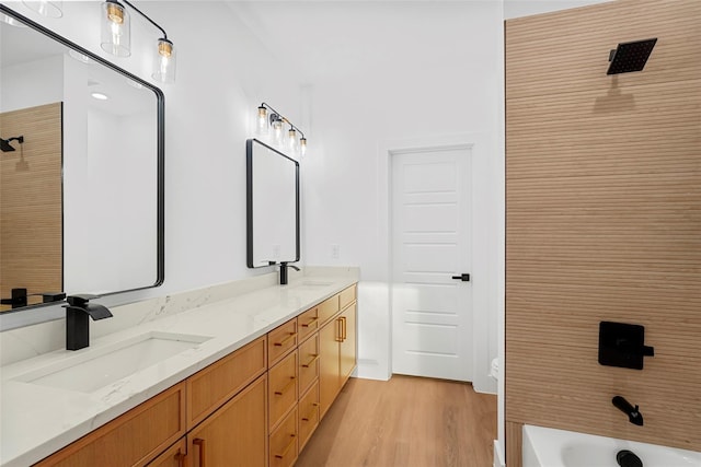 full bath with double vanity, wood finished floors, and a sink