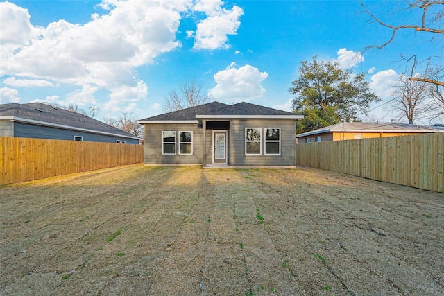 rear view of property featuring a yard and a fenced backyard