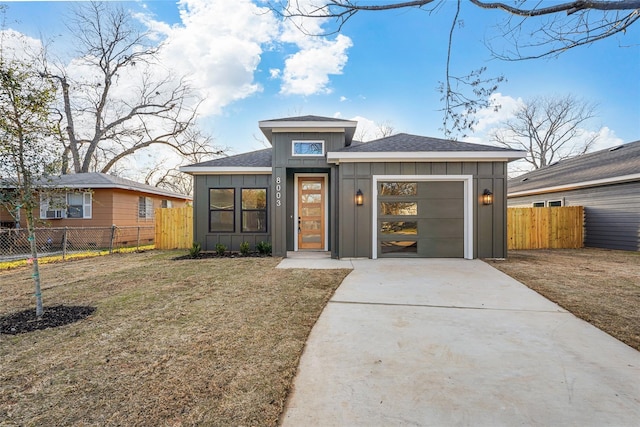 view of front of house featuring fence, driveway, roof with shingles, an attached garage, and board and batten siding