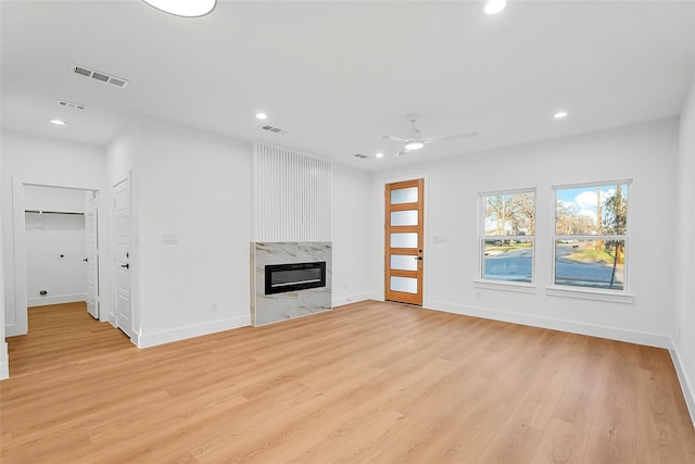 unfurnished living room featuring a high end fireplace, visible vents, recessed lighting, and light wood-style floors