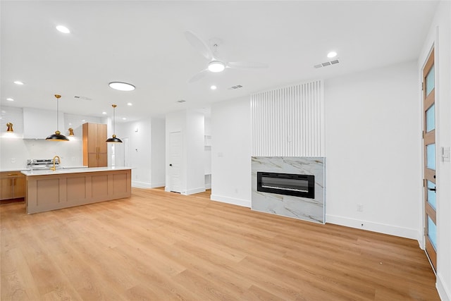 unfurnished living room featuring visible vents, light wood-style flooring, heating unit, recessed lighting, and a premium fireplace