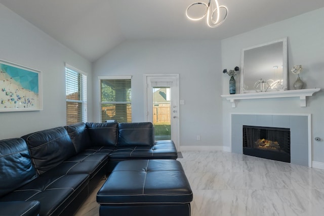 living area with a chandelier, baseboards, vaulted ceiling, and a tile fireplace