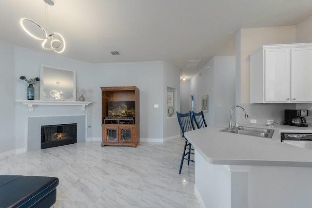 kitchen with marble finish floor, a sink, backsplash, white cabinets, and light countertops