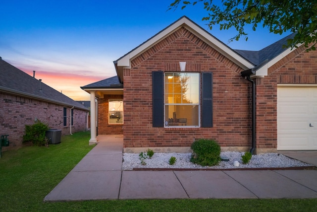 view of front of property with brick siding, a front lawn, an attached garage, and cooling unit