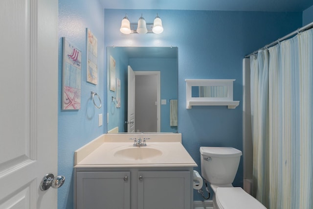 bathroom with toilet, vanity, and a textured wall