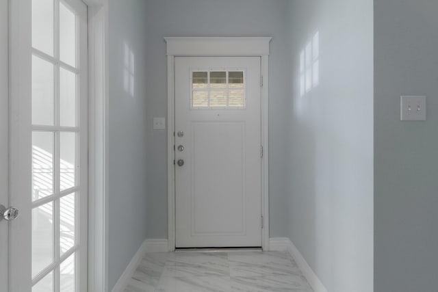 doorway to outside featuring baseboards and marble finish floor