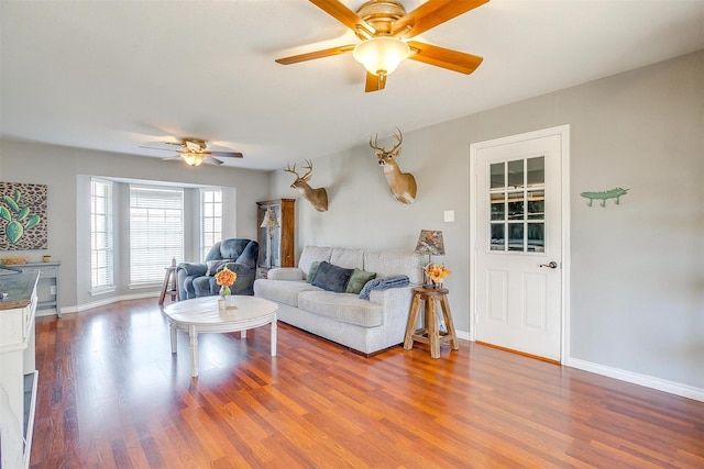 living area featuring baseboards, wood finished floors, and a ceiling fan