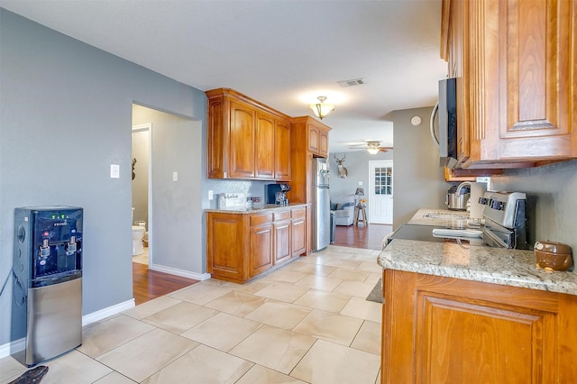 kitchen with brown cabinetry, baseboards, visible vents, ceiling fan, and stainless steel appliances