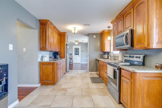 kitchen with brown cabinetry, visible vents, appliances with stainless steel finishes, and a sink