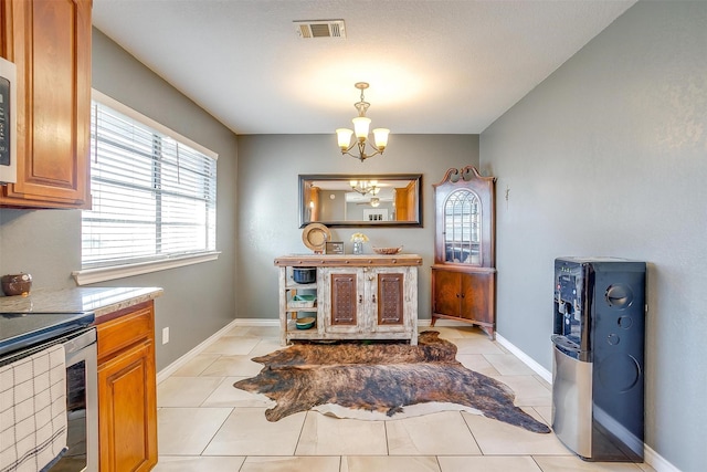 kitchen with visible vents, stainless steel appliances, light tile patterned floors, baseboards, and a chandelier