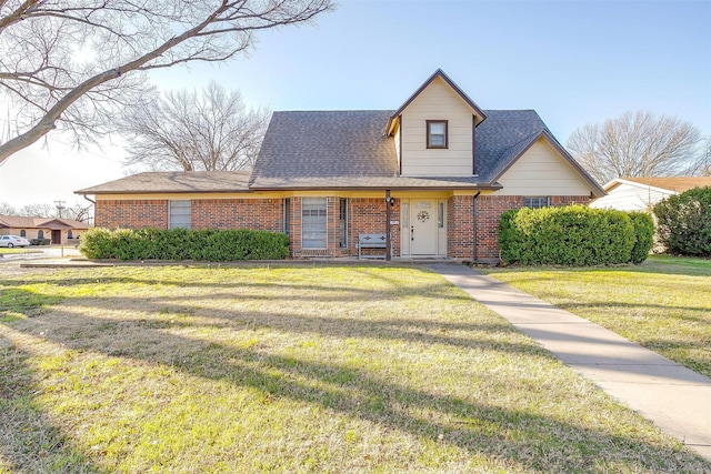 view of front of home featuring brick siding, a shingled roof, and a front yard