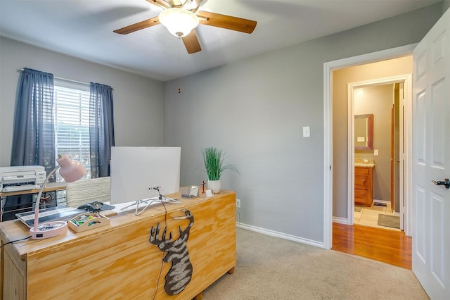 carpeted office space with baseboards and a ceiling fan