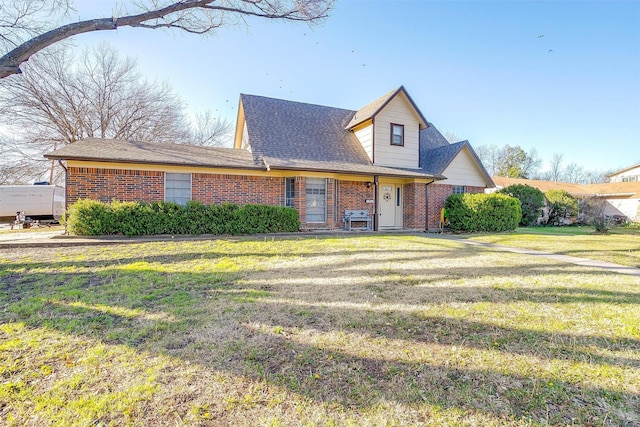 view of front facade featuring brick siding, a shingled roof, and a front yard