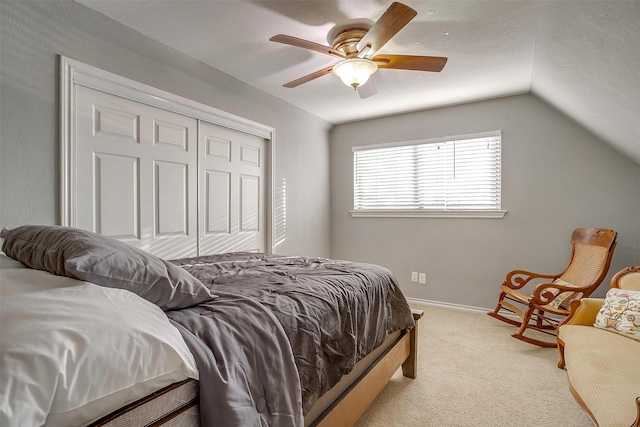 carpeted bedroom with vaulted ceiling, a ceiling fan, a closet, and baseboards