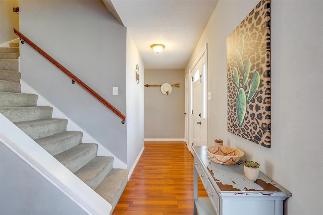 foyer featuring stairs, light wood-style flooring, and baseboards